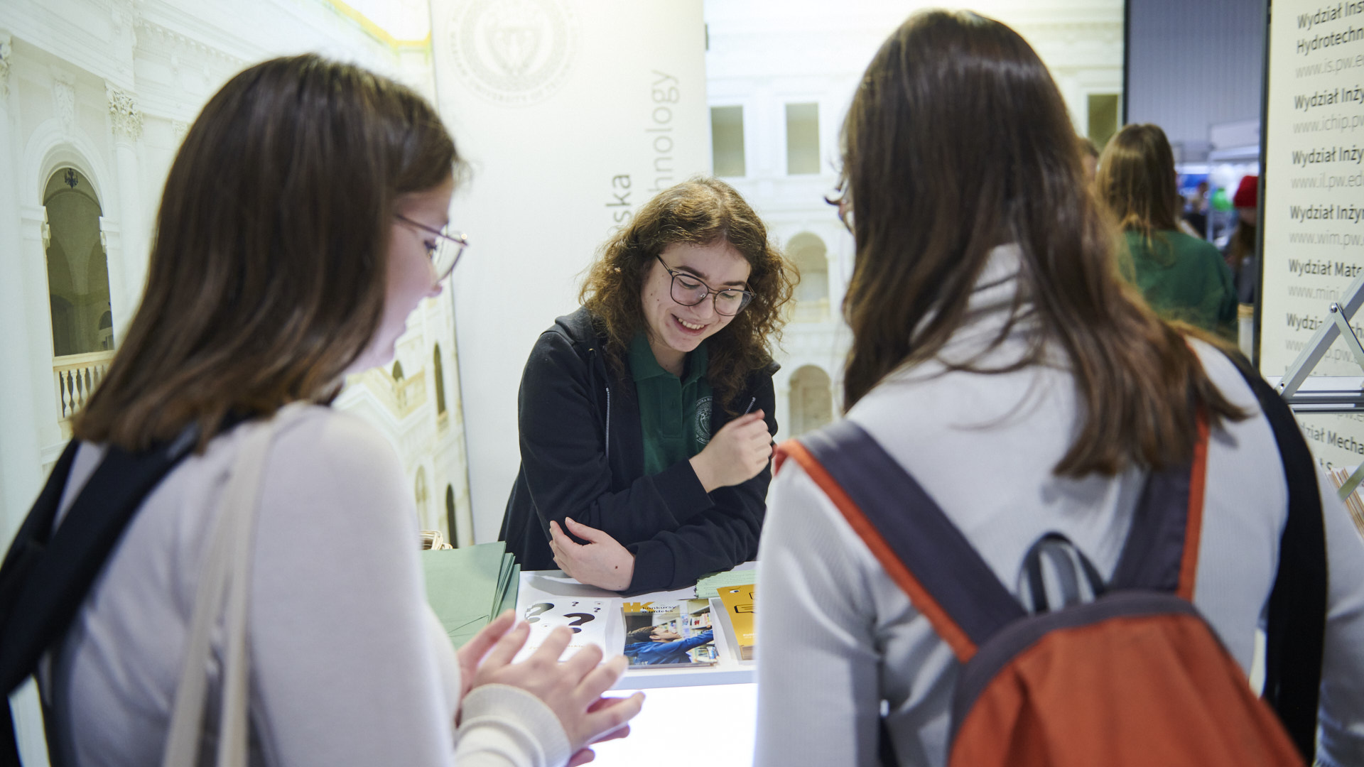 Na zdjęciu trzy osoby rozmawiające przy stoisku Politechniki na Międzynarodowym Salonie Edukacyjnym