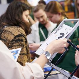 Na zdjęciu kilka osób przy stoisku Politechniki Warszawskiej na Międzynarodowym Salonie Edukacyjnym