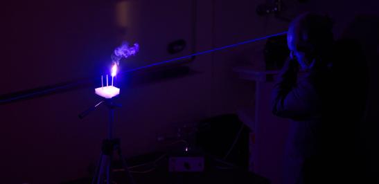 Na zdjęciu człowiek gaszący płomień przy pomocy lasera