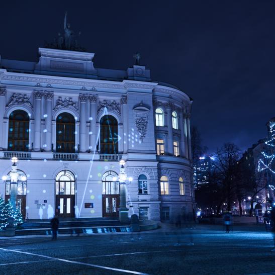 Na zdjęciu Gmach Główny PW po zmroku, ze świąteczną iluminacją i oświetlonymi drzewkami