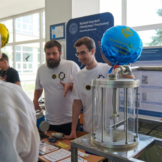 Na zdjęciu grupa osób przy instalacji chemicznej
