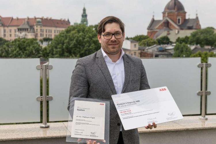 Dr inż. Maksym Figat trzymający dyplom i czek za wygraną w konkursie