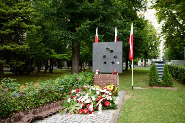 Zdjęcie pomnika batalionu "Golski" na terenie Politechniki Warszawskiej ze złożonymi kwiatami  zniczami