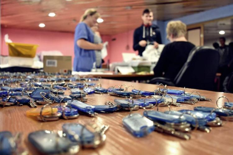 Zdjęcie kluczy leżących na stole i rozmawiających osób w tle