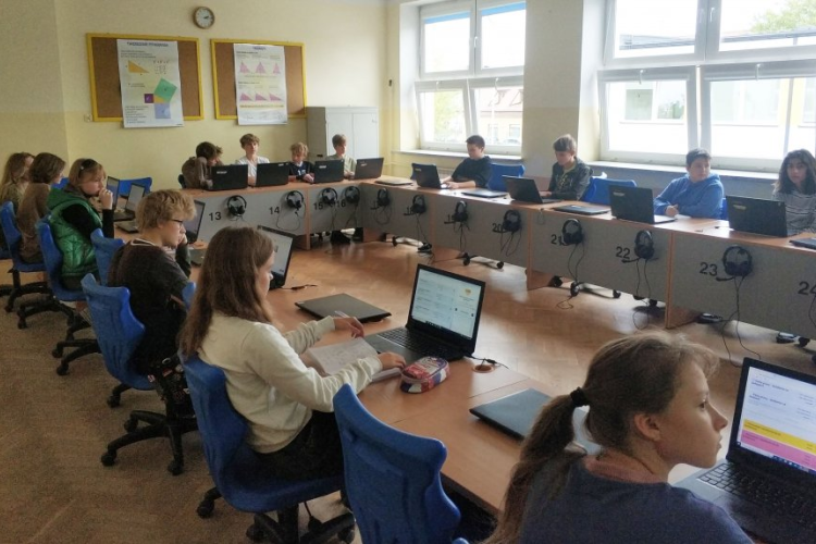 Zdjęcie uczniów siedzących przy komputerach i korzystających z systemu zeszyt.online