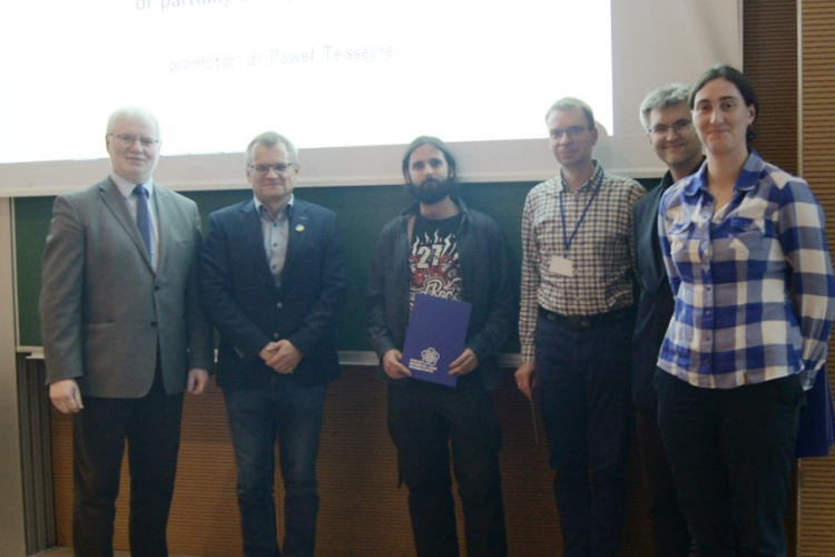Zdjęcie jednego z laureatów konkursu w towarzystwie promotora pracy i organizatorów