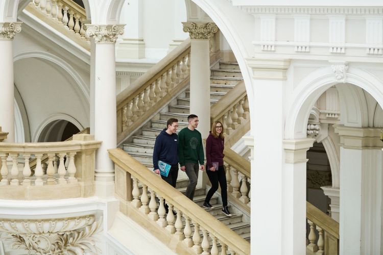 Na zdjęciu troje studentów idących po schodach w Gmachu Głównym PW