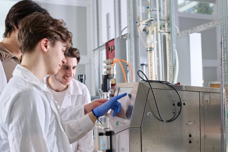Na zdjęciu trzy osoby stojące przy sprzęcie w laboratorium
