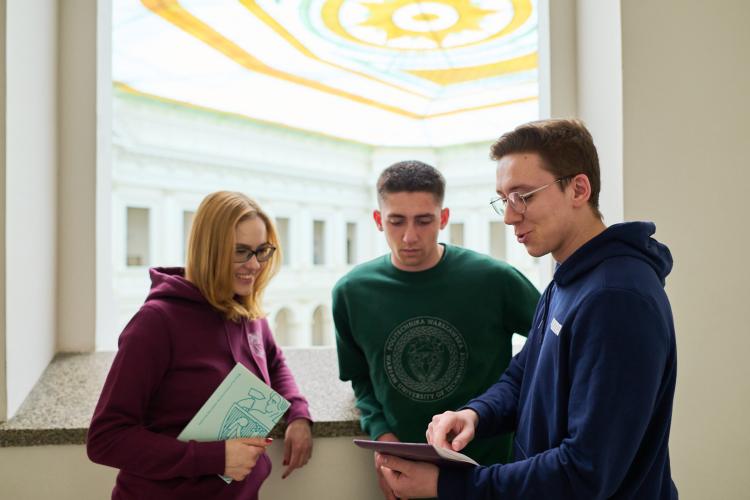 Na zdjęciu troje studentów stojących w Gmachu Głównym PW