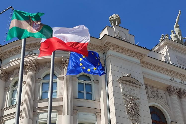 Na zdjęciu fragment Gmachu Głównego oraz wiszące przed nim flagi: Politechniki Warszawskiej, Polski, Unii Europejskiej 
