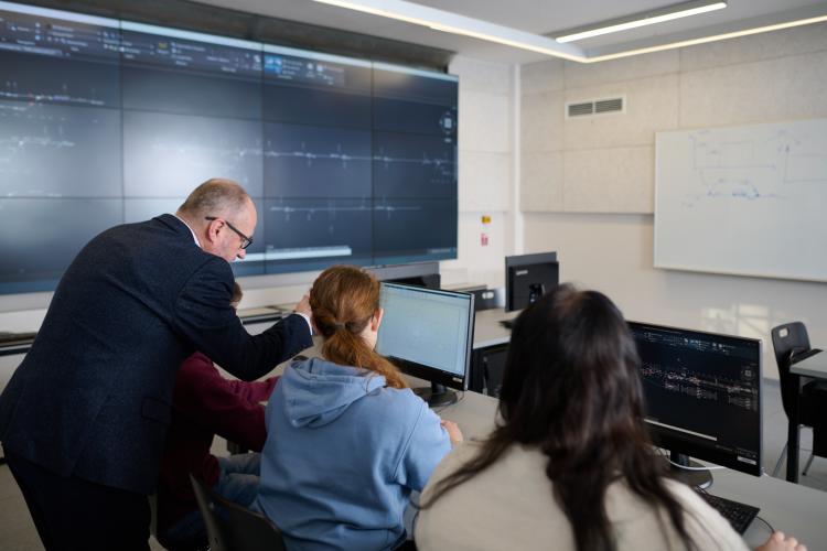 Zajęcia w laboratorium, prowadzący tłumaczy coś studentom