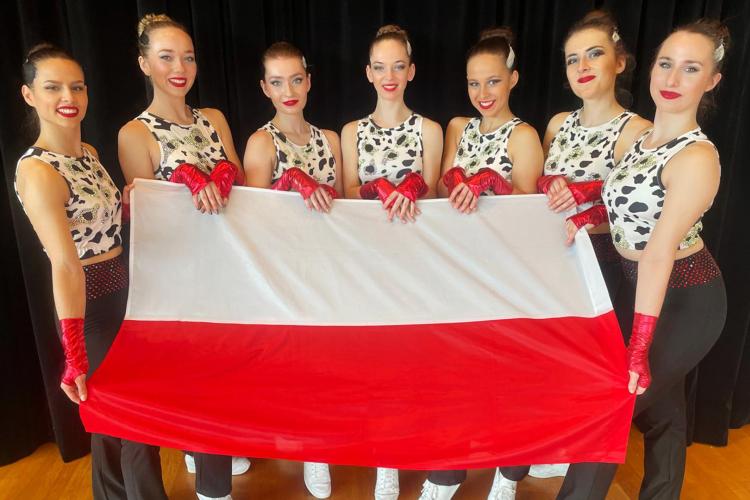 Na zdjęciu siedem zawodniczek z sekcji aerobiku sportowego. Stoją, trzymając przed sobą flagę Polski