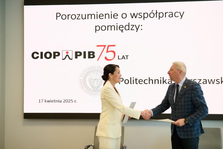Na zdjęciu prof. Mariusz Malinowski, Prorektor ds. Nauki oraz Agnieszka Szczygielska, Dyrektorka CIOP-PIB stoją na tle ekranu i ściskają sobie dłonie