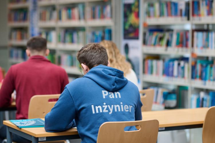 Na zdjęciu troje studentów siedzących w ławkach w Bibliotece Głównej