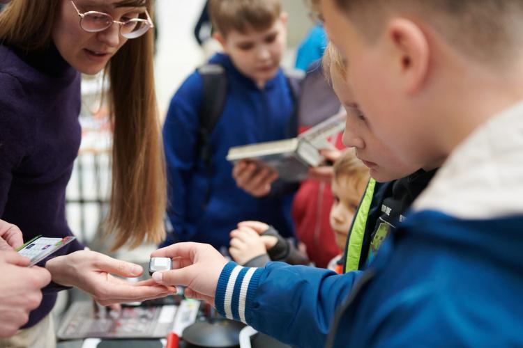 Na zdjęciu ludzie przy stanowisku Studenckiego Koła Inżynierii Fotonicznej na Nocy Muzeów