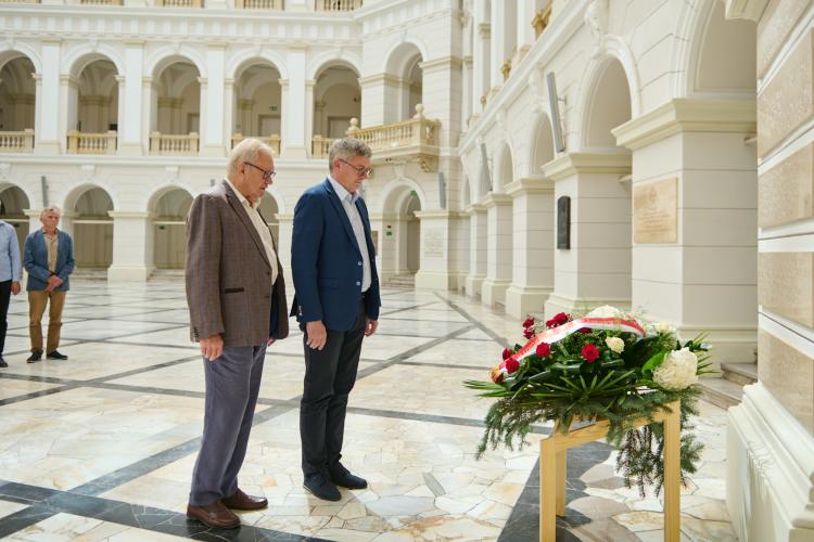 Prorektor PW ds. Ogólnych prof. Mirosław Karpierz oraz Prezes Stowarzyszenia Absolwentów i Przyjaciół PW prof. Andrzej Kolasa stoją przy wieńcu złożonym pod tablicą w Gmachu Głównym Politechniki Warszawskiej