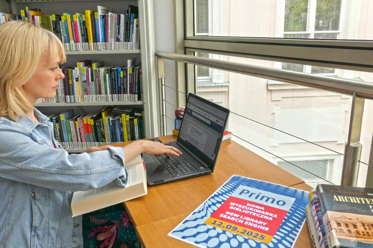 Doktorantka korzysta z komputera na tle regałów z książkami