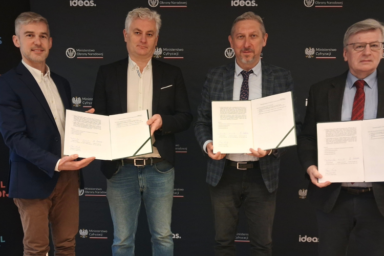 Zdjęcie przedstawia czterech mężczyzn trzymających w rękach podpisane porozumienie