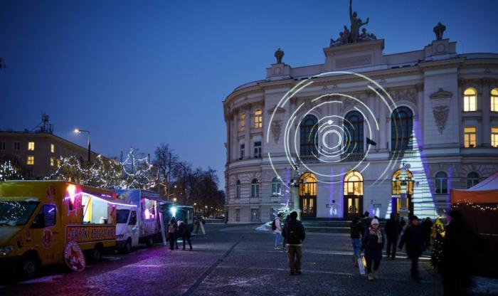 Zdjęcie Gmachu Głównego Politechniki Warszawskiej ze świąteczną iluminacją i ludźmi uczestniczącymi w kiermaszu