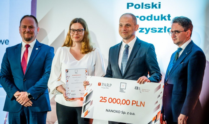 Zdjęcie przedstawicieli firmy Nanoxo pozujących z czekiem za wyróżnienie w konkursie Polski Produkt Przyszłości oraz wręczających nagrody 