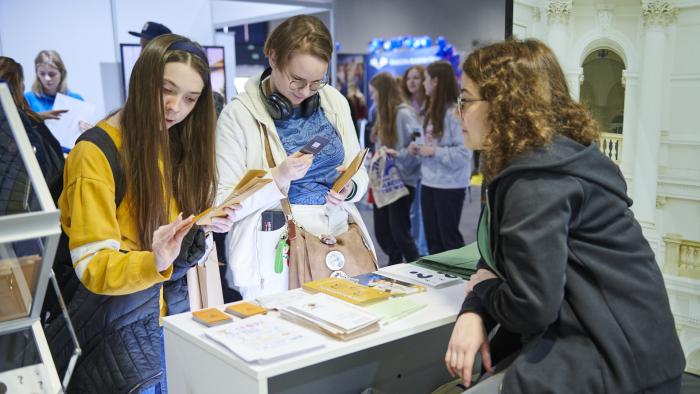 Na zdjęciu trzy osoby rozmawiające przy stoisku Politechniki na Międzynarodowym Salonie Edukacyjnym