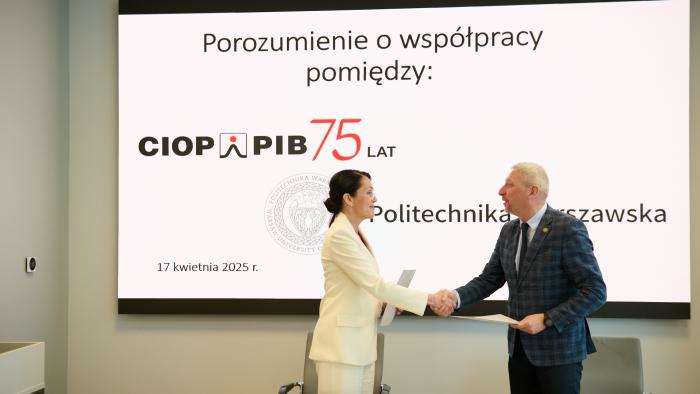 Na zdjęciu prof. Mariusz Malinowski, Prorektor ds. Nauki oraz Agnieszka Szczygielska, Dyrektorka CIOP-PIB stoją na tle ekranu i ściskają sobie dłonie