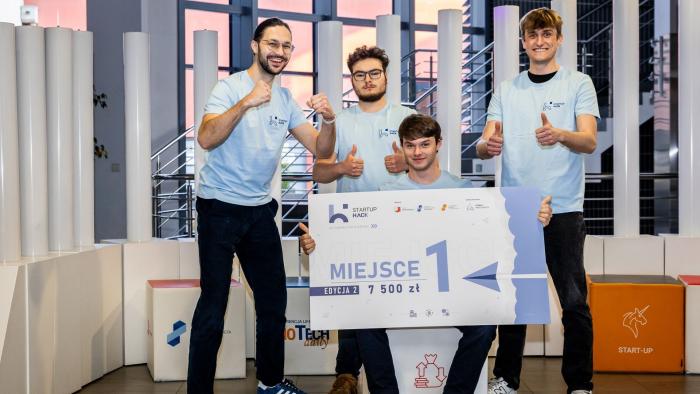 Na zdjęciu czterej młodzi mężczyźni z czekiem za zwycięstwo w Hackathonie StartupHack