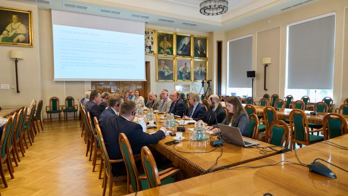 Na zdjęciu grupa osób siedzących przy stole w Sali Senatu Politechniki Warszawskiej