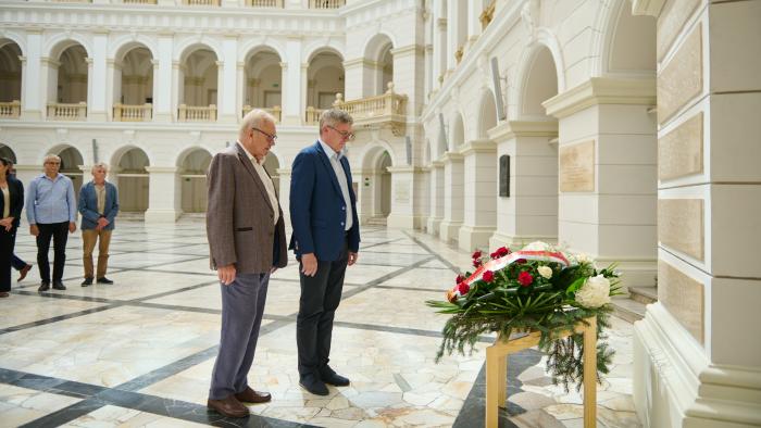 Prorektor PW ds. Ogólnych prof. Mirosław Karpierz oraz Prezes Stowarzyszenia Absolwentów i Przyjaciół PW prof. Andrzej Kolasa stoją przy wieńcu złożonym pod tablicą w Gmachu Głównym Politechniki Warszawskiej
