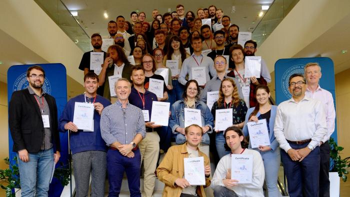 Na zdjęciu grupa kilkudziesiąciu osób stojących na schodach w Centrum Zaawansowanych Materiałów i Technologii PW CEZAMAT 