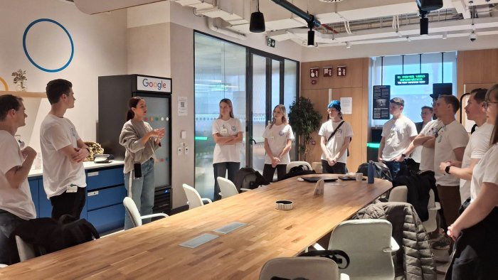 Na zdjęciu grupa ludzi stoi wokół stołu