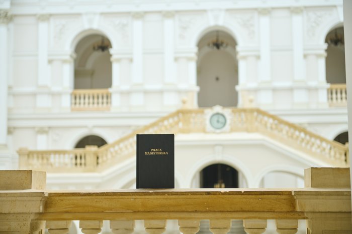 Na zdjęciu: okładka pracy magisterskiej na tle Dużej Auli w Gmachu Głównym PW