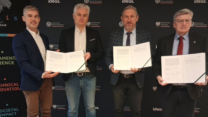 Zdjęcie przedstawia czterech mężczyzn trzymających w rękach podpisane porozumienie