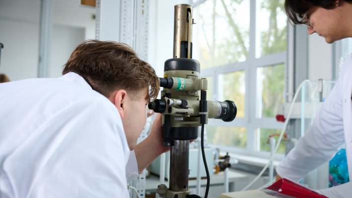 Na zdjęciu: student pracuje z mikroskopem w laboratorium chemicznym