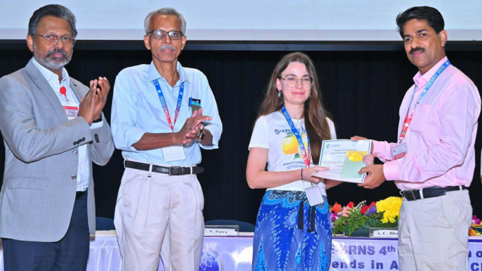 Na zdjęciu są 4 osoby. Jedna z nich, kobieta, odbiera dyplom