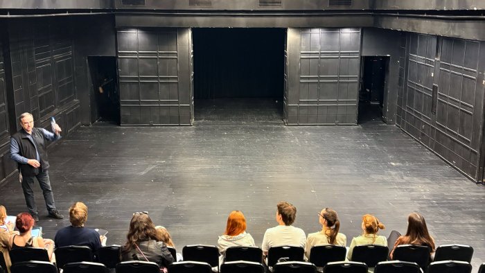 Na zdjęciu wizyta studentów w Teatrze Narodowym, na scenie stoi i opowiada dyrektor techniczny  inż. arch. Zbigniew Kośka