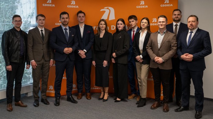 Na zdjęciu stoi grupa ludzi. Od lewej: Piotr Kurkowski (p.o. Zastępcy Generalnego Dyrektora GDDKiA), dr hab. inż. Grzegorz Kacprzak (Promotor pracy), inż. Piotr Derlacz, Daniel Kosiński (Dyrektor Generalny Urzędu), prof dr. hab. inż. Anna Siemińska-Lewandowska, (Promotor pracy), Paweł Woźniak (p.o. Generalnego Dyrektora GDDKiA), dr hab. inż. Janusz Bohatkiewicz (Przewodniczący Kapituły Konkursowej)