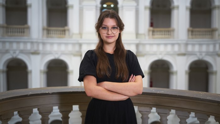 Na zdjęciu: Emilia Bartnik, studentka Wydziału GiK, na tle Dużej Auli PW