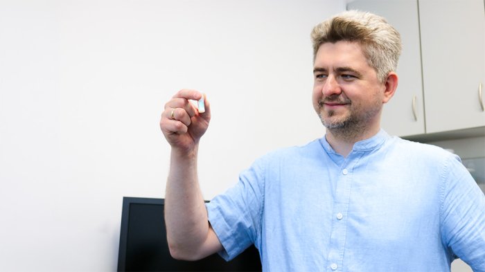 Na zdjęciu dr inż. Kamil Orzechowski trzyma ciekły kryształ zamknięty w fiolce