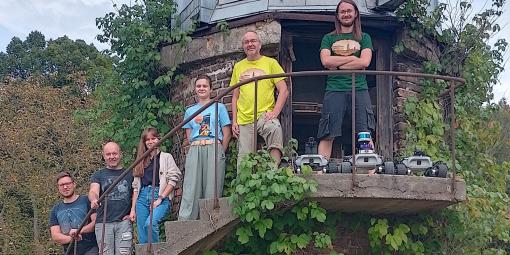 Na zdjęciu sześć osób stojących na schodach dawnego obserwatorium astronomicznego w Józefosławiu oraz łaziki marsjańskie