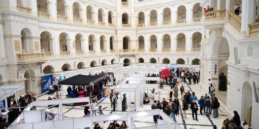 Na zdjęciu stanowiska kół naukowych oraz grupa ludzi w Dużej Auli Gmachu Głównego