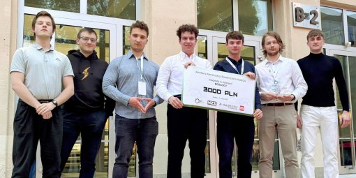 Na zdjęciu siedmiu studentów stojących na tle budynku