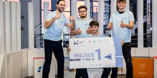 Na zdjęciu czterej młodzi mężczyźni z czekiem za zwycięstwo w Hackathonie StartupHack