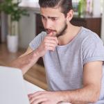 Zdjęcie mężczyzny siedzącego przed ekranem laptopa
