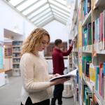 Studenci szukający książek w bibliotece