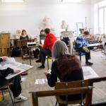Na zdjęciu studenci architektury siedzący przy pulpitach i rysujący