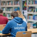 Na zdjęciu troje studentów siedzących w ławkach w Bibliotece Głównej