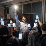 Na zdjęciu mężczyzna trzymający włączoną żarówkę oraz grupa osób trzymających telefony komórkowe