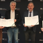 Zdjęcie przedstawia czterech mężczyzn trzymających w rękach podpisane porozumienie