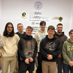 Zdjęcie przedstawia ośmiu studentów stojących na tle ściany z logotypem Wydziału Elektrycznego PW